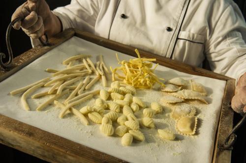 a chef holding a tray of food on a cutting board at Hotel Villa Ducale in Taormina