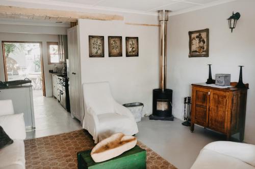 ein Wohnzimmer mit weißen Möbeln und einem Holzofen in der Unterkunft Compass View in Nieu-Bethesda