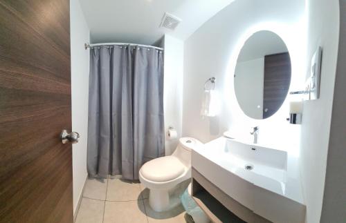 a bathroom with a toilet and a sink and a mirror at Condo 9, San Francisco Tower in San Salvador