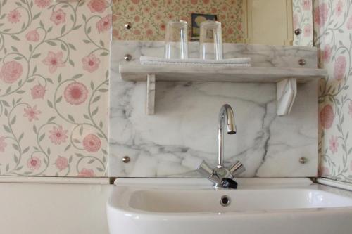 a white sink in a bathroom with a marble wall at Hotel Museumzicht in Amsterdam
