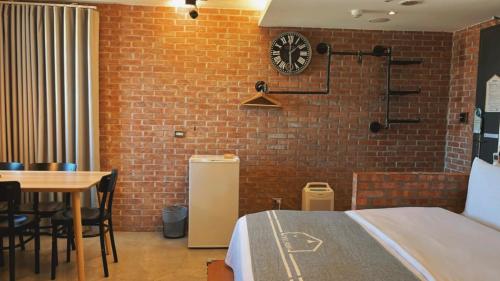 a room with a bed and a table and a clock at Chill Roof Hotel in Taipei