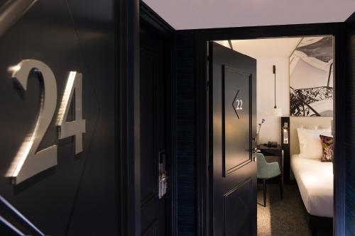a door to a room with a bed and a desk at Hôtel Gustave in Paris