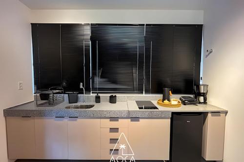 a kitchen with a counter top with black blinds at Villa Naluri - Seu Refúgio a 50 metros da praia em Japaratinga in Japaratinga