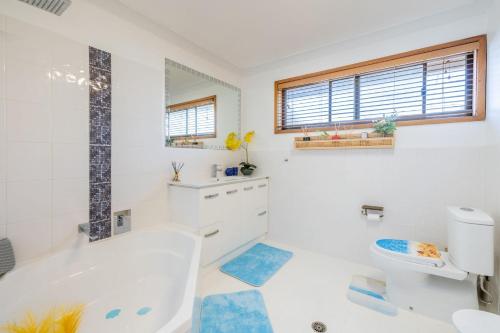 a bathroom with a tub and a toilet and a sink at 4 Gilchrist Rd - pet friendly, air con, Wi-Fi in Salamander Bay