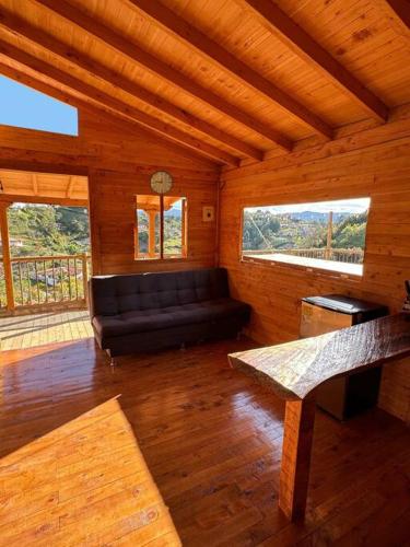 a living room with a black couch in a cabin at La Cabaña de Blue in Guarne