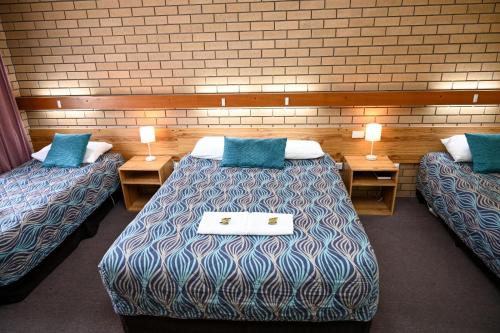 a room with two beds with blue pillows at Holbrook Town Centre Motor Inn in Holbrook