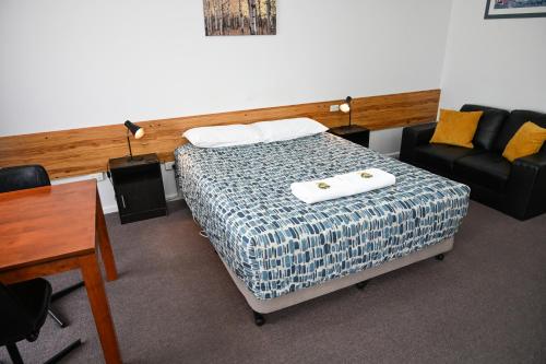 a room with a bed and a table and a couch at Holbrook Town Centre Motor Inn in Holbrook