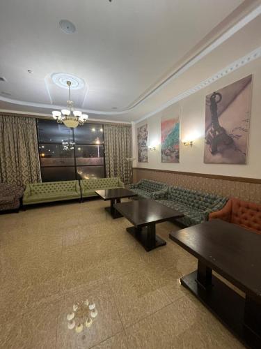 a living room with tables and couches and a window at Sunkar Hotel in Atyraū