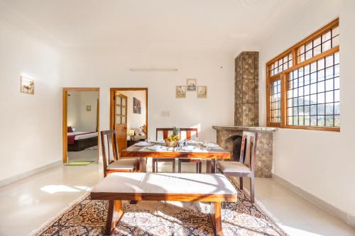 a dining room with a table and chairs and a fireplace at Alaya Stays Rose 3BHK Cottage Fenced by Hills with Fireplace in Bhowāli