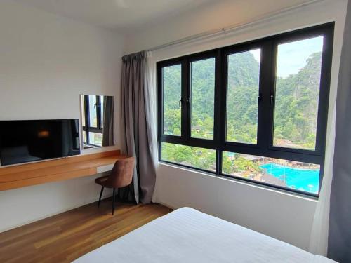 una camera da letto con finestra e scrivania con televisore di IPOH Sunway Onsen Suites and Tambun GuestHouse by uBook a Tambun