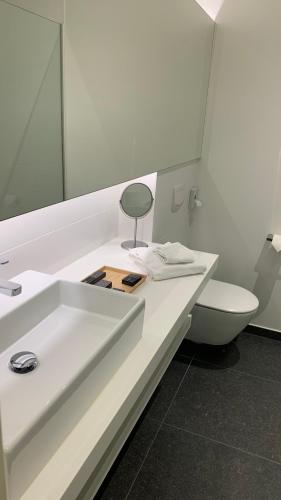 a bathroom with a white sink and a toilet at Boutique hotel-restaurant De Lindehoeve in Tessenderlo