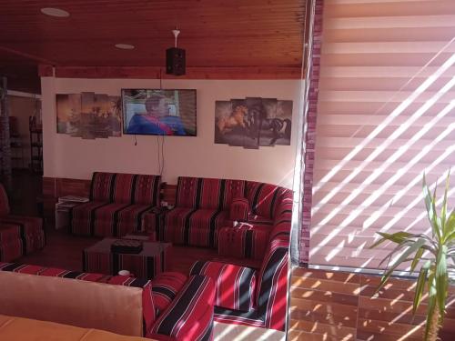 a living room with two red couches and a tv at Petra voyager Hostel in Wadi Musa