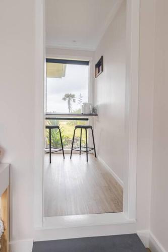 a white room with a table and two stools at On The Beach in Napier