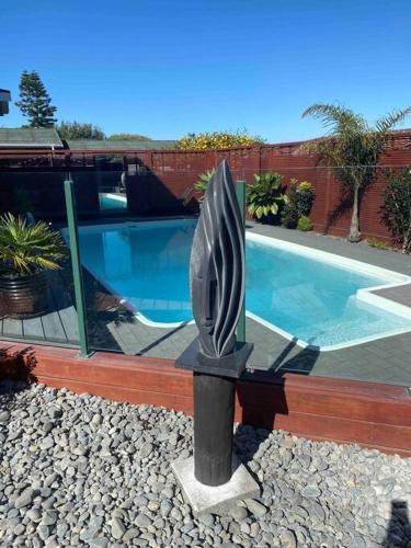 a statue in a yard next to a swimming pool at On The Beach in Napier
