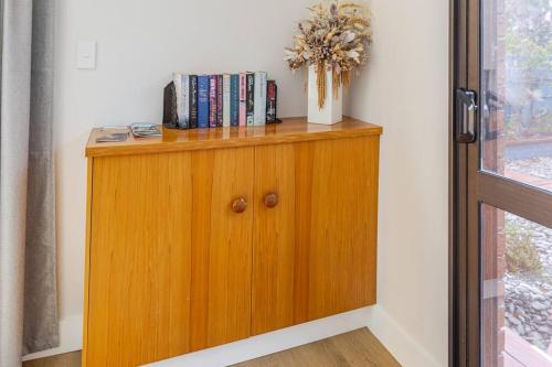 a wooden cabinet with books on it next to a window at On The Beach in Napier