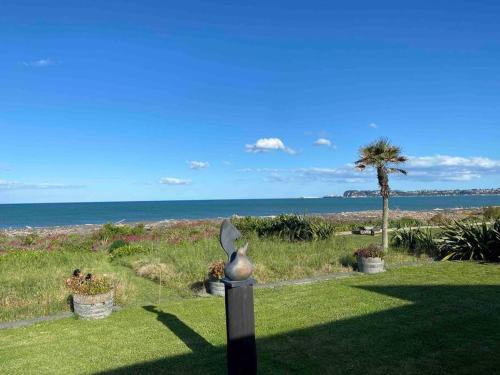 a statue of a bird on a post in front of the ocean at On The Beach in Napier