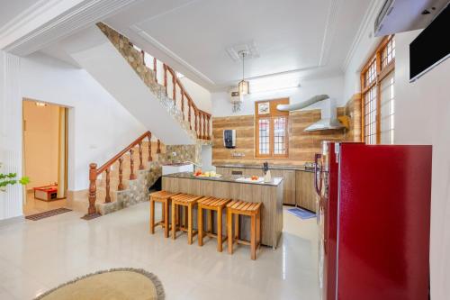 a kitchen with a red refrigerator and wooden cabinets at Alaya Stays 3BHK Rose Haven near Kainchi Dham in Bhowāli