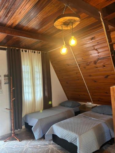 two beds in a room with a wooden ceiling at Chalé Estância do Coruja in Salesópolis