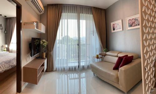 a bedroom with a couch and a large window at Sky condo by Grace in Chon Buri
