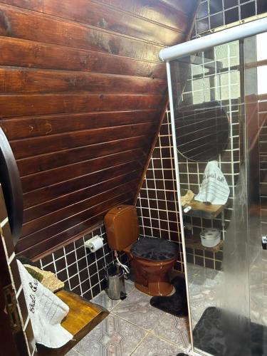 a bathroom with a toilet and a wooden wall at Chalé Estância do Coruja in Salesópolis