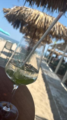 a glass of wine sitting on a table next to an umbrella at Apartament MaGiFa Mamaia Nord in Năvodari