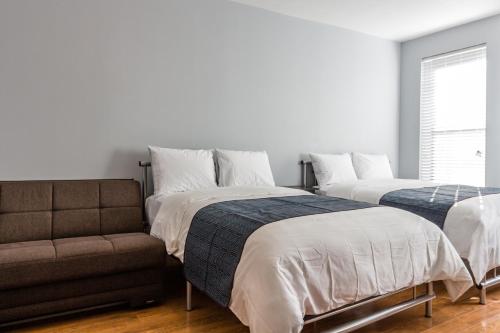 a bedroom with two beds and a couch at The Park Ave North in New York