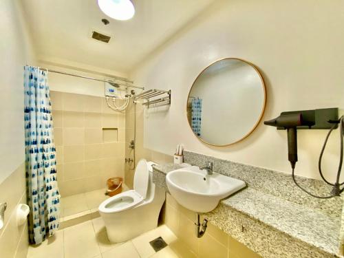 a bathroom with a toilet and a sink and a mirror at Infina Towers in Manila