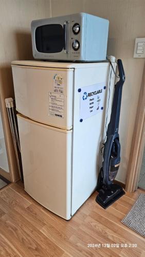 a microwave on top of a refrigerator with a vacuum at Hongdae Residence-5 1min from Hongik Uni station Exit #1 in Seoul