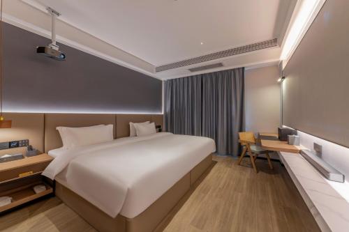 a bedroom with a large bed and a desk at Luyue Hotel Movie Hotel Huaqiangbei Convention and Exhibition Center Branch in Shenzhen