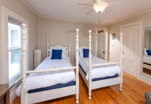 two white beds in a bedroom with a ceiling fan at Main House at One Long Beach in York Beach
