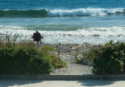 a person sitting on a bench looking at the ocean at Main House at One Long Beach in York Beach