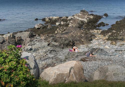 two people sitting on the rocks near the water at Main House at One Long Beach in York Beach