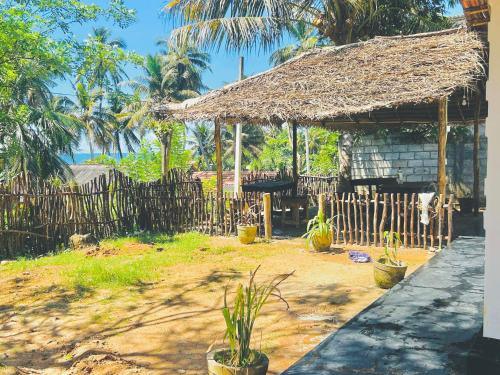 a house with a straw roof and a fence at Newton House in Hiriketiya