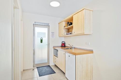 a small kitchen with a sink and a refrigerator at Tussock Peak Lodge in Hanmer Springs