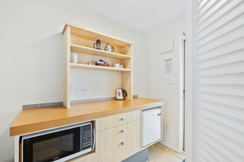 a kitchen with a counter with a microwave and a refrigerator at Tussock Peak Lodge in Hanmer Springs