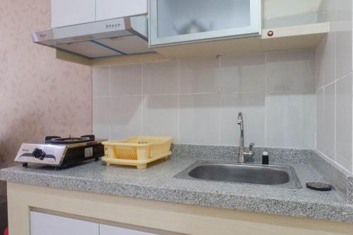 a kitchen counter with a sink and a microwave at Spacious & Comfortable Studio Apartment at Bale Hinggil By Travelio in Medokanayu
