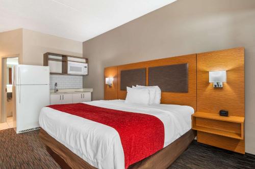 a bedroom with a large bed with a red blanket at MainStay Suites Springfield IL in Springfield