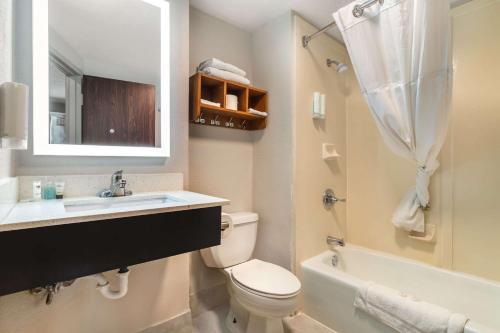 a bathroom with a toilet and a sink and a tub at MainStay Suites Springfield IL in Springfield