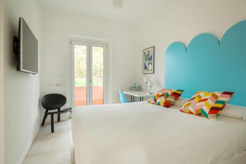 a bedroom with a large white bed and a chair at Spacebility Beach - self check-in in Quartu SantʼElena