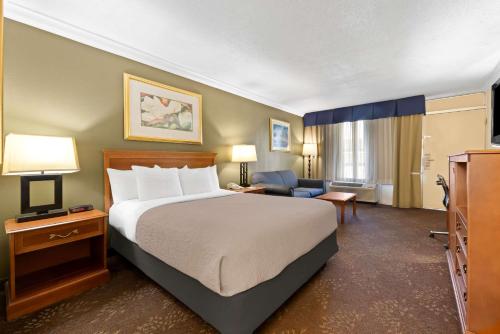 a hotel room with a large bed and a chair at Quality Inn Morgan City in Morgan City