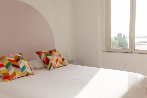 a bedroom with a white bed with two colorful pillows at Spacebility Airport - self check-in in Cagliari