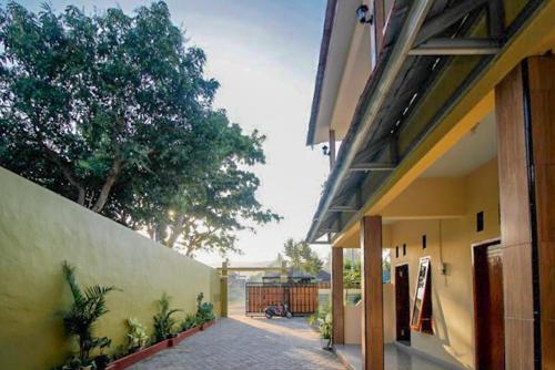 a courtyard of a building with a tree in the background at Urbanview Griya Lota Guest House Banyuwangi in Ketapang