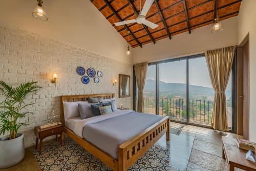 ein Schlafzimmer mit einem Bett und einem großen Fenster in der Unterkunft SaffronStays Ikigai in Wādhiware