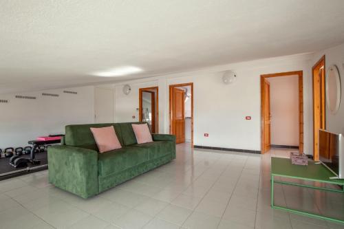 a living room with a green couch and a television at Spacebility Airport - self check-in in Cagliari