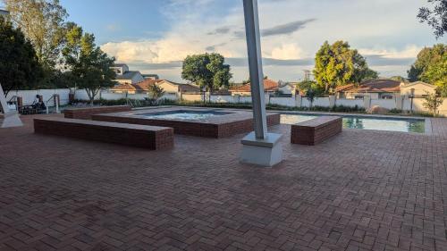 un patio con una fuente con bancos y un poste en 2-BR Apt, Pool access & Balcony, Paulshof, en Sandton