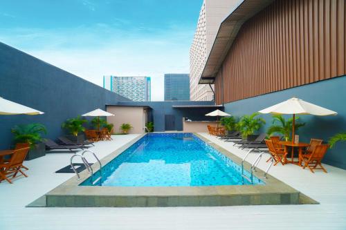 a swimming pool on top of a building with chairs and umbrellas at Swiss-Belinn Cawang in Jakarta