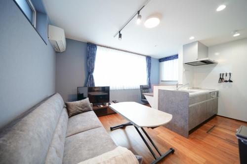 a living room with a couch and a table at Casa Antonio A モダン空間 駅近&空港バス 駐車場付 in Sapporo