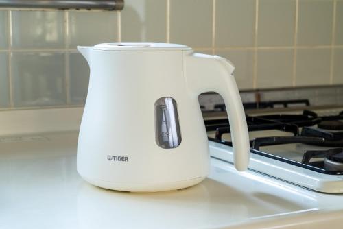 a white tea kettle sitting on top of a stove at すずかのおやど Suzuka Inn in Suzuka