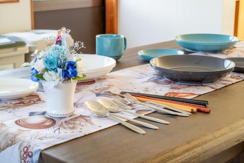 a table with plates and utensils and a vase of flowers at すずかのおやど Suzuka Inn in Suzuka