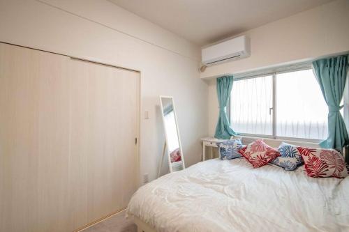 a bedroom with a bed with pillows and a window at 横須賀アロハハウス702 in Yokosuka